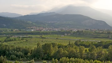 Une vue panoramique d’une vallée, avec une voie ferrée, des montagnes lointaines et des bâtiments dispersés.