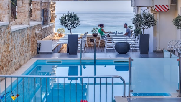 A poolside area with a view of the sea, a bar, and outdoor seating. - Alexis Hotel (Chania)