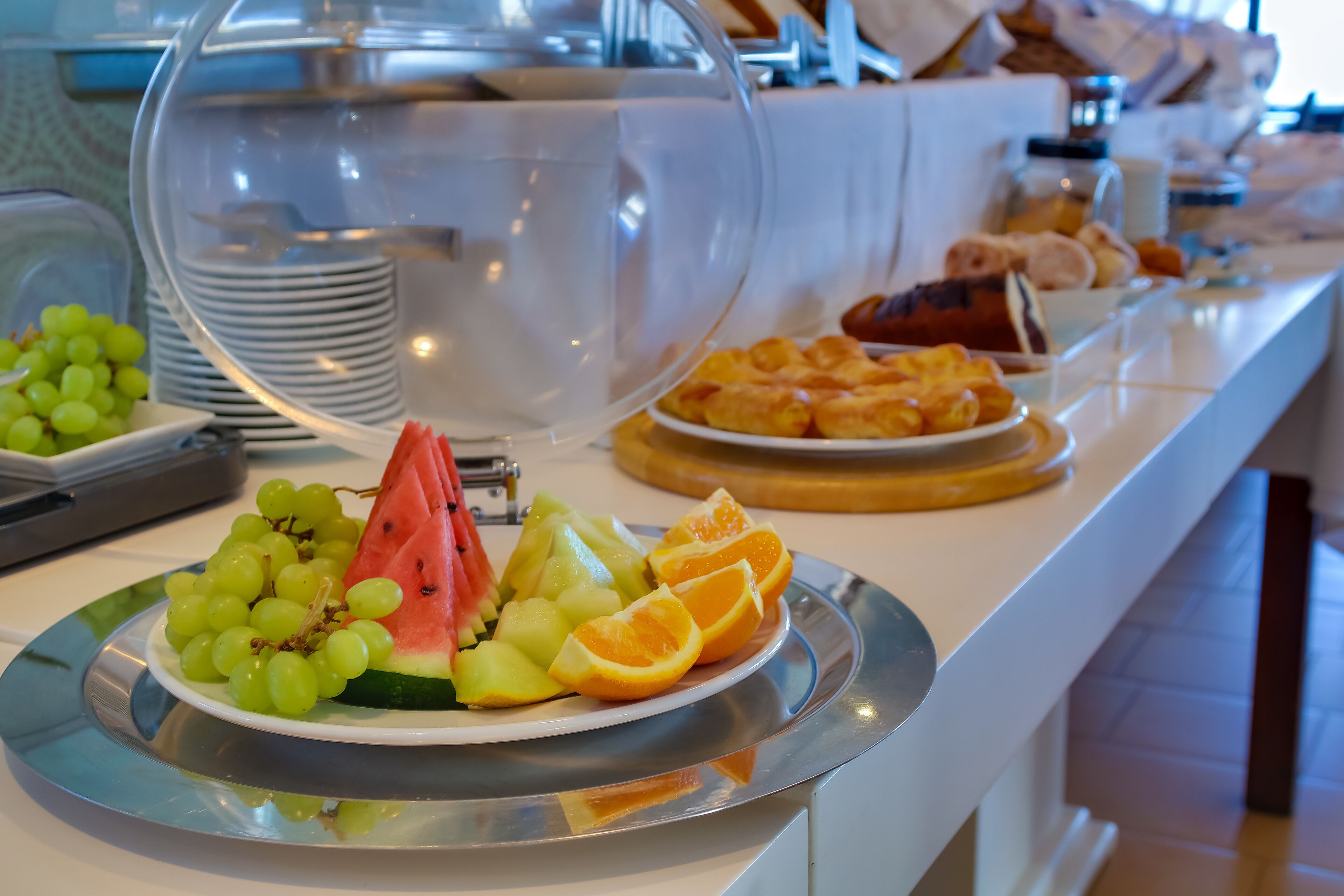 A buffet with various fruits and pastries.