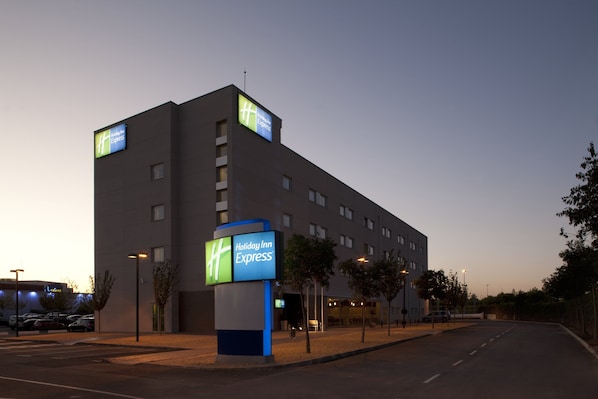 Edificio de Holiday Inn Express con un letrero llamativo, un estacionamiento y un cielo despejado.
