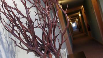 A hallway with a decorative tree sculpture in a glass vase.
