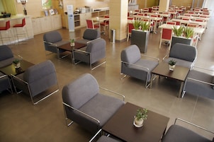 Amplio espacio interior con varias mesas y sillas, algunas con plantas en macetas.