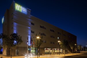 A Holiday Inn Express building with a modern design, multiple floors, and a visible restaurant on the ground level.