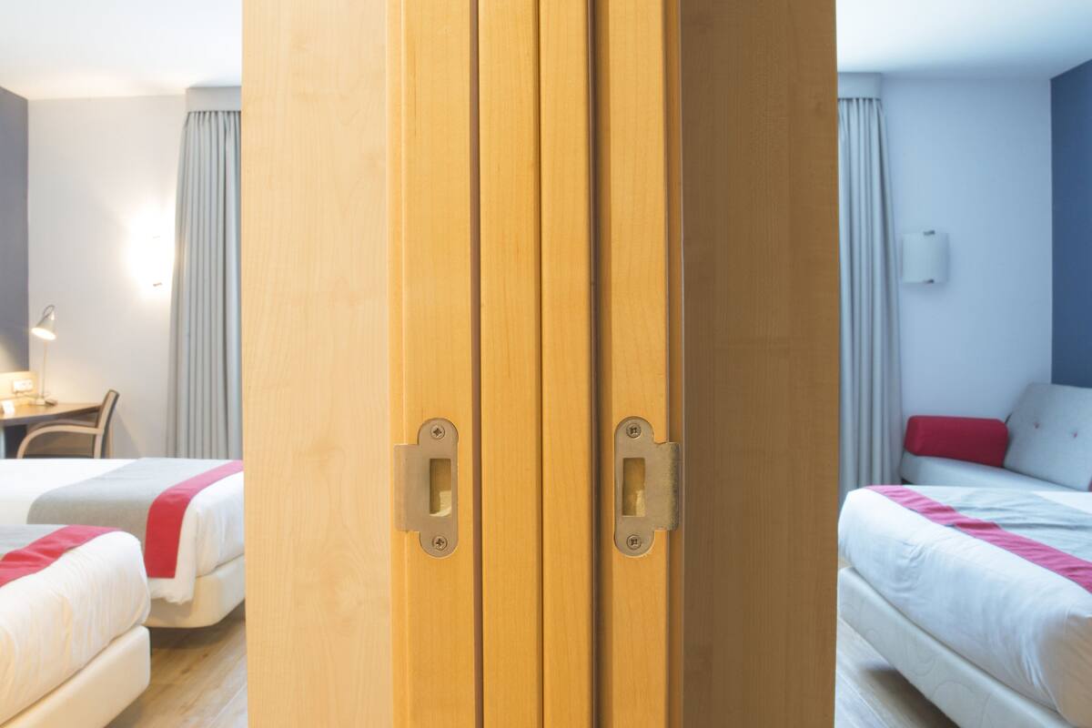 Hotellihuone, jossa on kaksi sänkyä, työpöytä ja vaatekaappi.