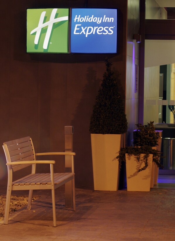 A bench, a planter with a small tree, and a Holiday Inn Express sign.