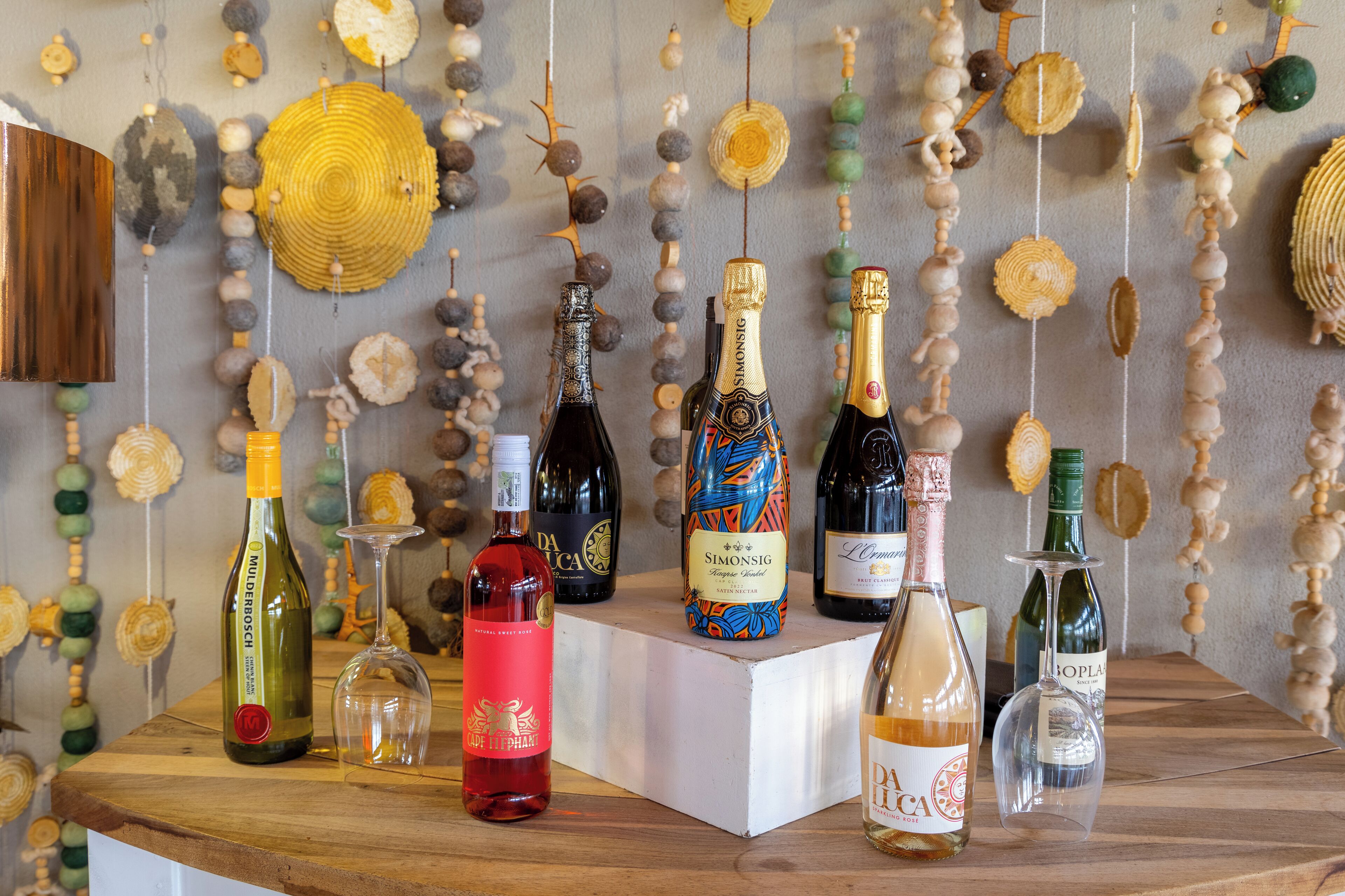 A selection of wine bottles on a wooden surface with a decorative wall in the background.