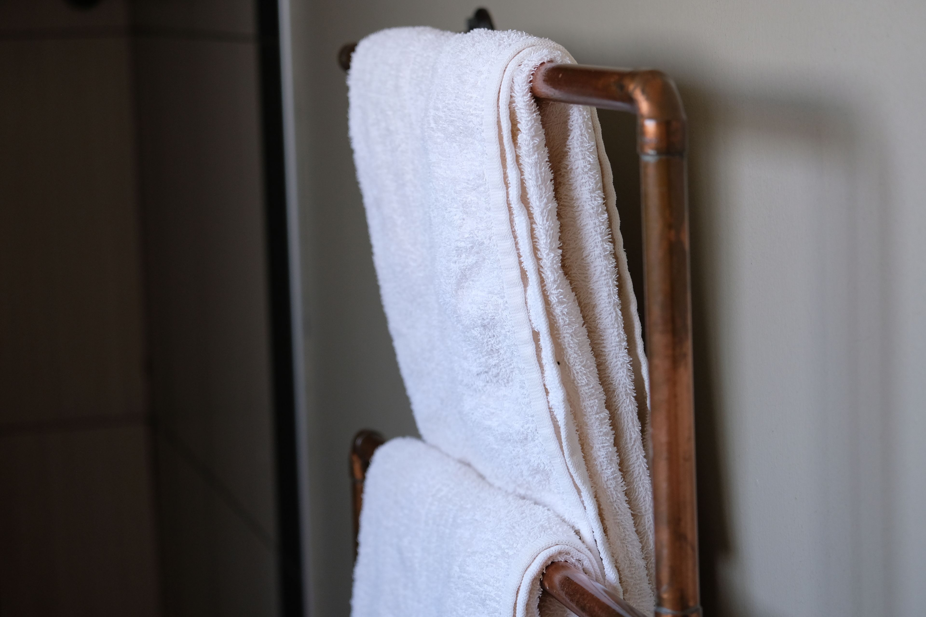 A white towel hanging on a wooden towel rack.