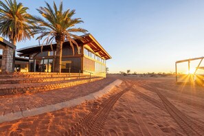 Edifici modern amb façana de pedra, grans finestres i zona d'entrada pavimentada.