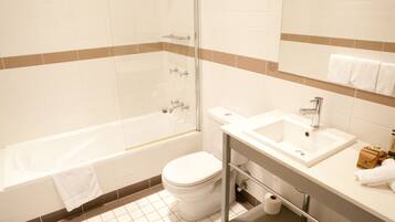 A bathroom with a bathtub, toilet, sink, and glass shower enclosure.