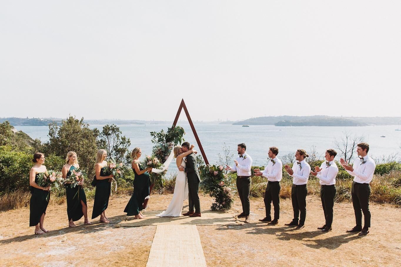 Ceremonia de boda con vistas al mar y colinas al fondo.