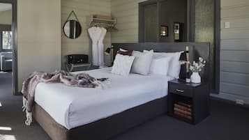 A modern bedroom with a large bed, bedside tables, a robe, and a mirror.