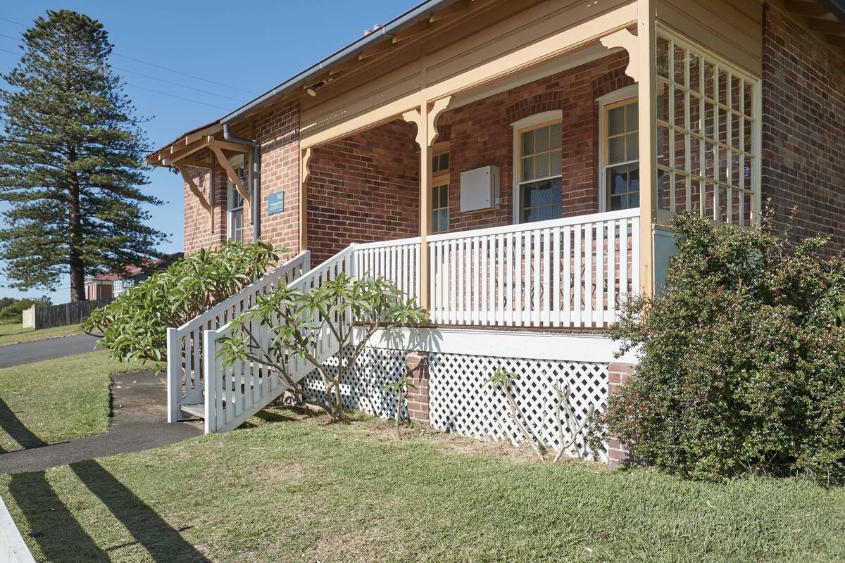 A brick building with a porch, a white picket fence, and a sign that reads 'S2'.