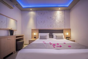 Ein modernes Hotelzimmer mit einem Bett, Nachttischen, einem Schreibtisch und einer Decke mit blauer Beleuchtung.