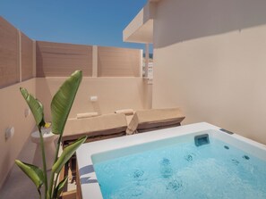 Un espace bien-être comprenant un jacuzzi, des chaises longues et une grande plante.