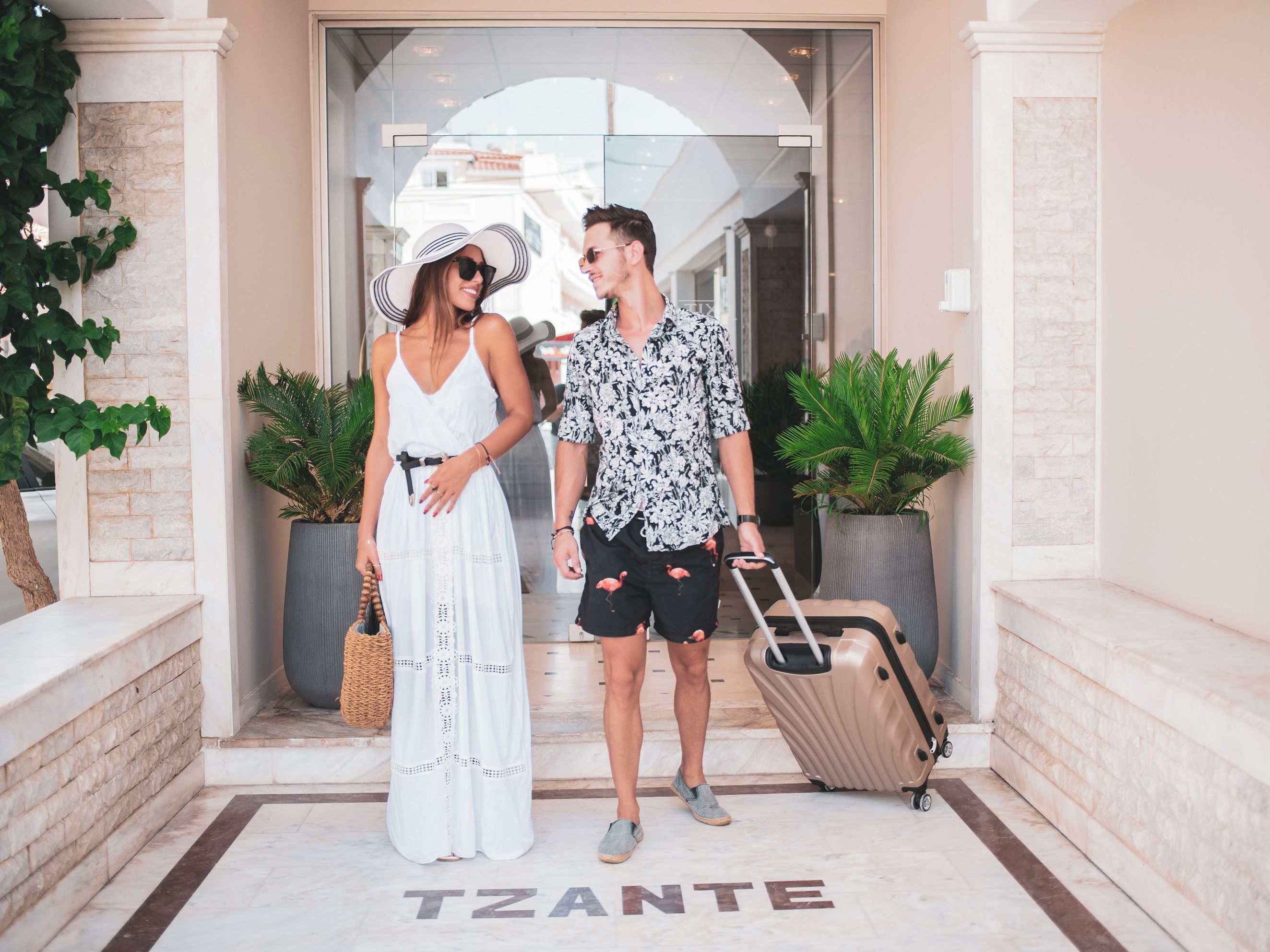 A couple standing in front of a building entrance with a sign that reads 'TZANTE'.
