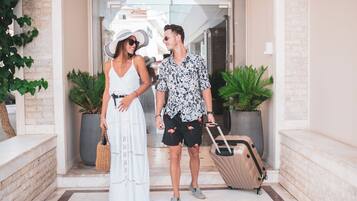 A couple standing in front of a building entrance with a sign that reads 'TZANTE'.