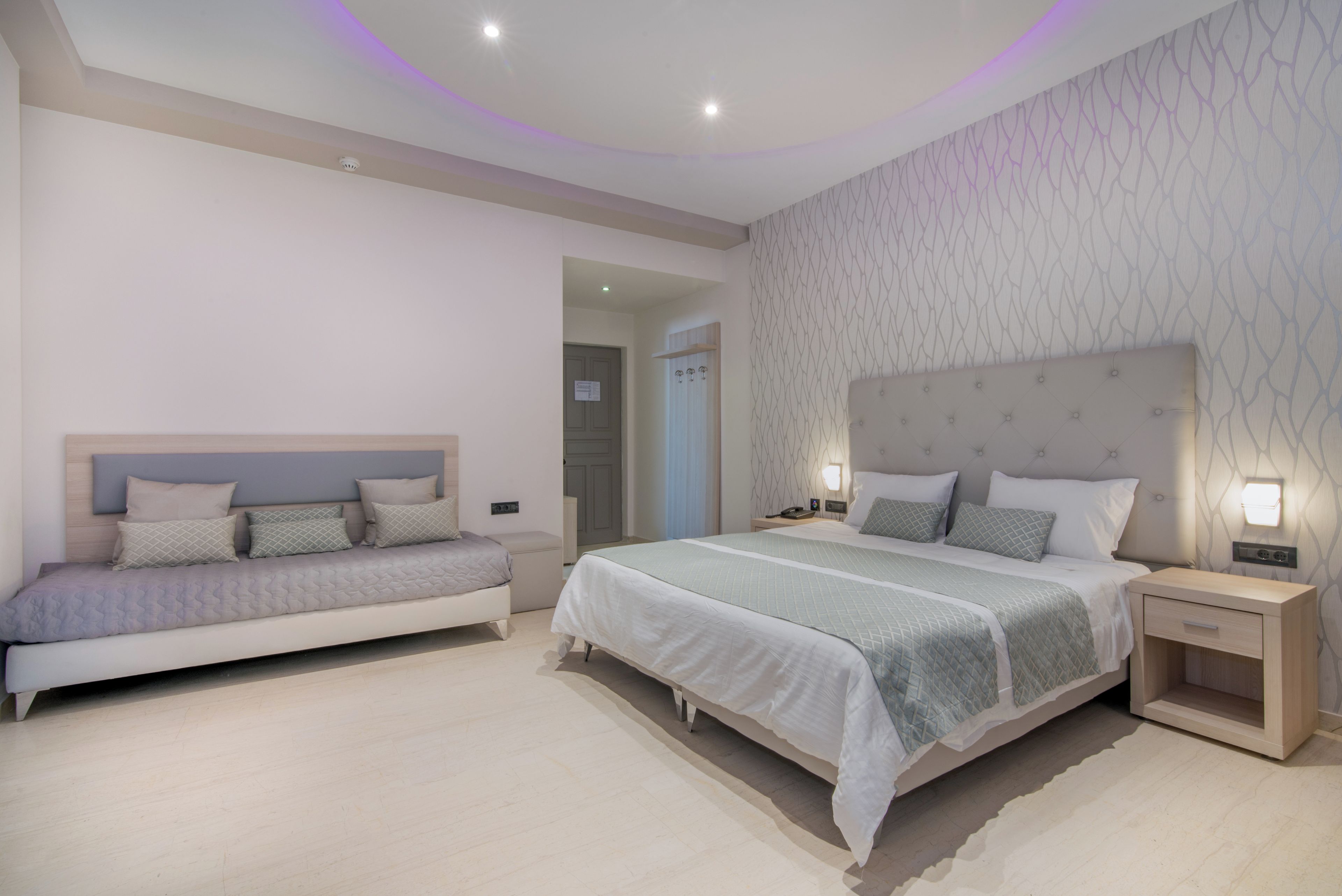 Un dormitorio moderno con dos camas, una mesita de noche y una lámpara de pared.