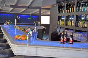 A bar area with a marble countertop, various bottles, and a fan in the background. - Tzante Hotel Zakynthos Adults Only (Zakynthos)
