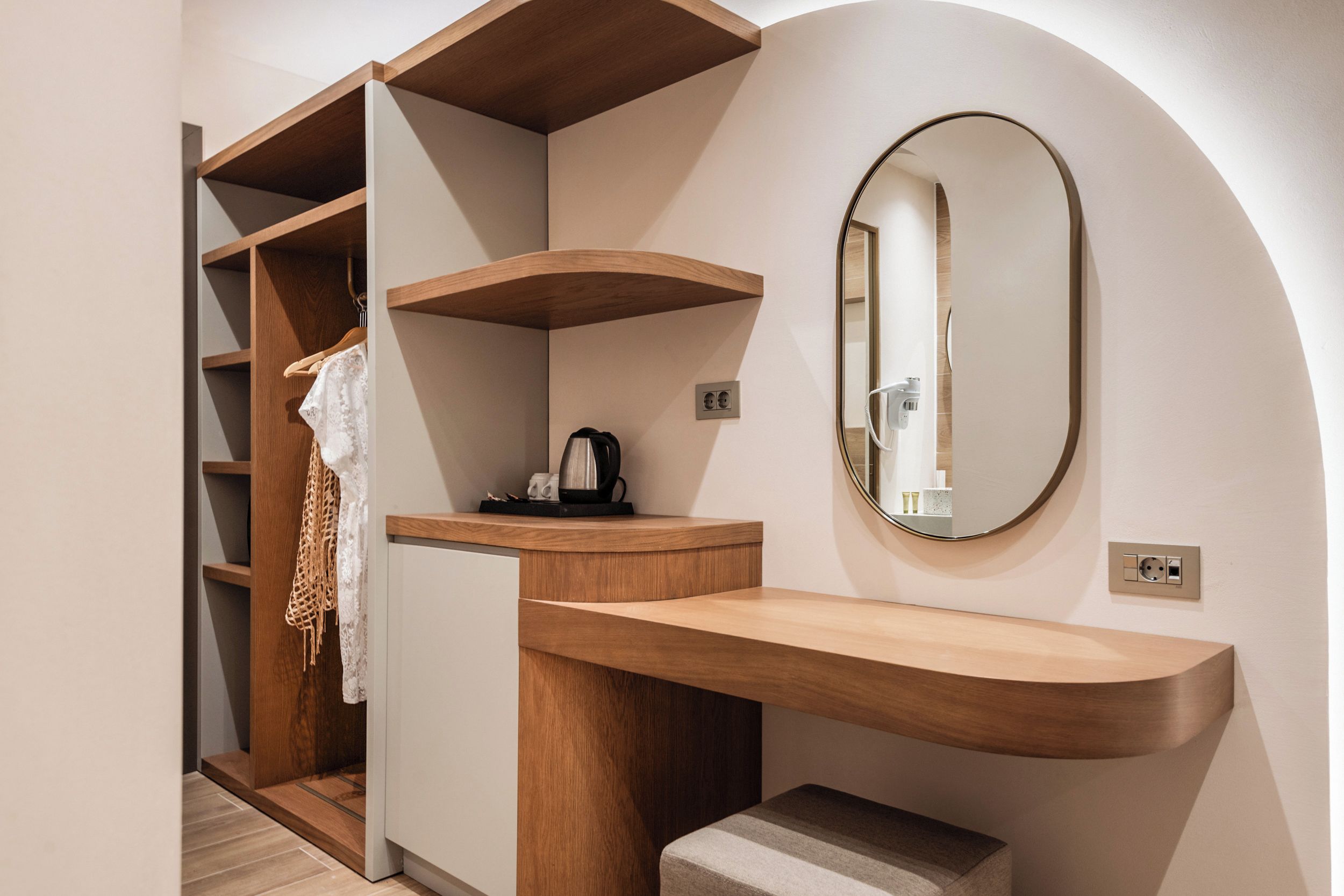 Un baño moderno con tocador de madera, un espejo y una estantería empotrada.