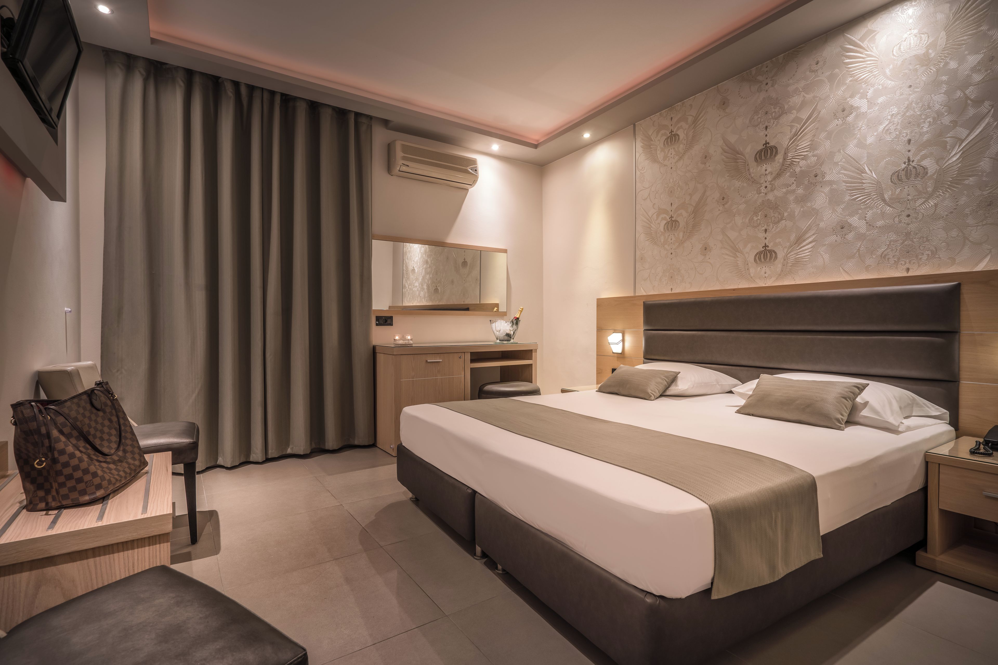 Una habitación de hotel con una cama grande, un escritorio, una silla, un armario y un espejo.