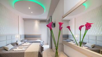 A modern hotel room with a large bed, a bedside table, a mirror, and a vase with flowers.