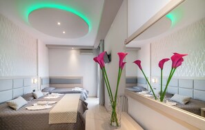 A modern hotel room with a large bed, a bedside table, a mirror, and a vase with flowers. - Tzante Hotel Zakynthos Adults Only (Zakynthos)