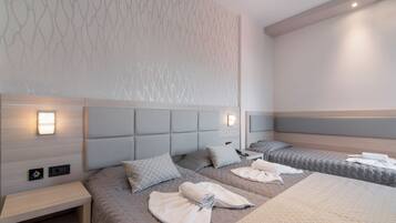 A modern hotel room with a large bed, a bedside table, and a wall-mounted light fixture.