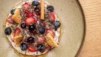 Un postre con fresas, arándanos y una galleta sobre un plato.