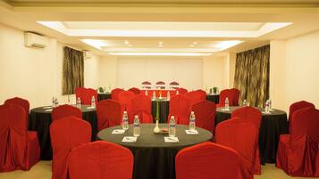 A conference room with round tables, red chairs, and black tablecloths.