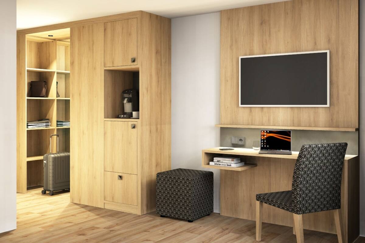 Een kamer met een houten garderobe, een bureau met een laptop, een stoel en een koffer.