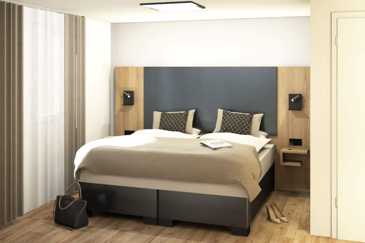 Een moderne slaapkamer met een bed, nachtkastjes en een handtas op de vloer.