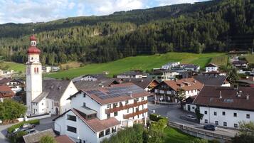 A town with a prominent church tower, modern buildings, and a green hillside.