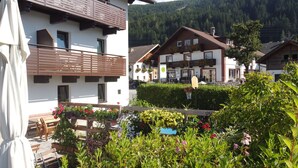 A traditional chalet-style building with a balcony, surrounded by lush greenery and a mountain backdrop. - Gästehaus Elisabeth (Tulfes)