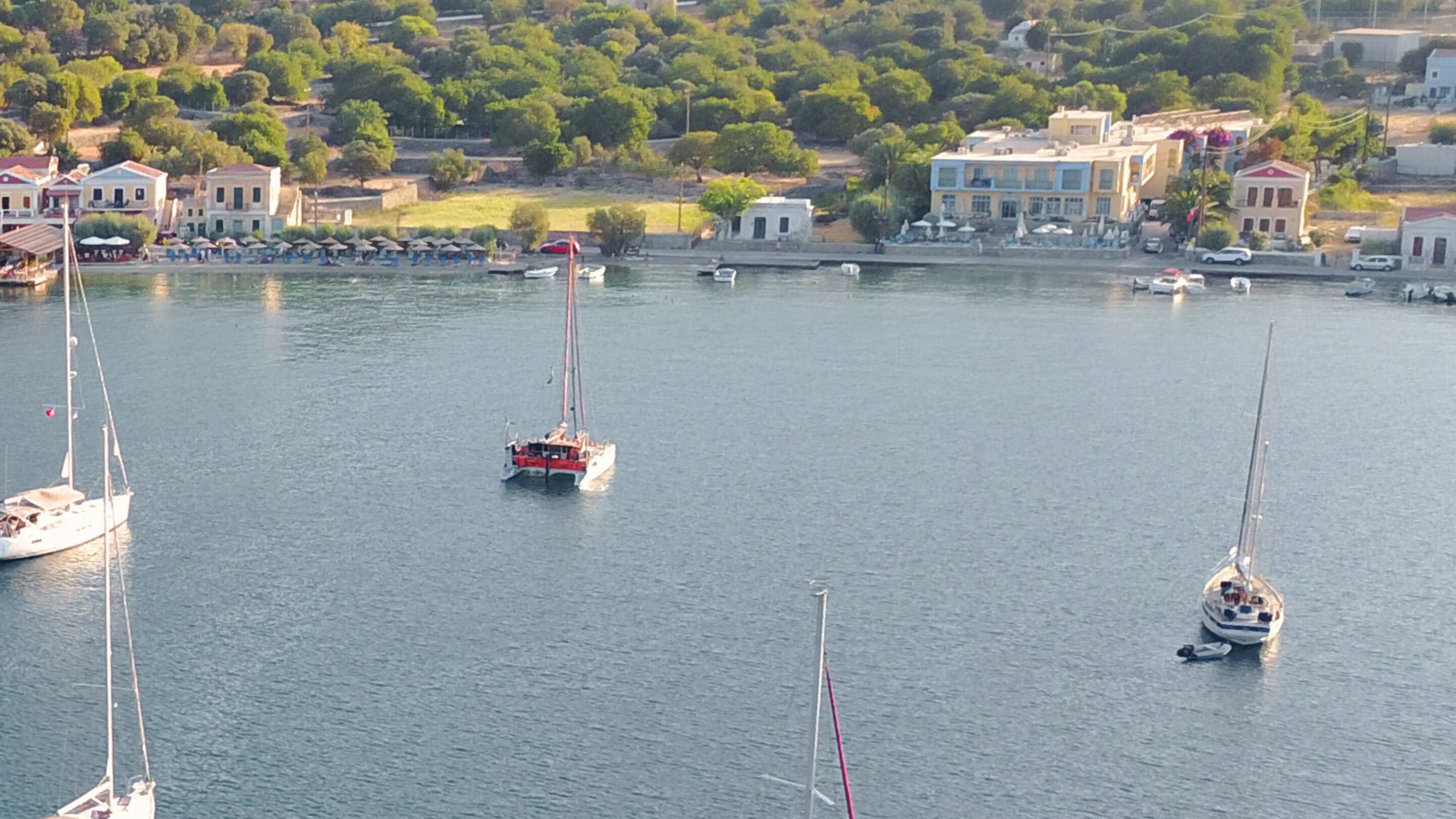 Marina com vários barcos, incluindo veleiros e um barco a motor, atracados à beira-mar.
