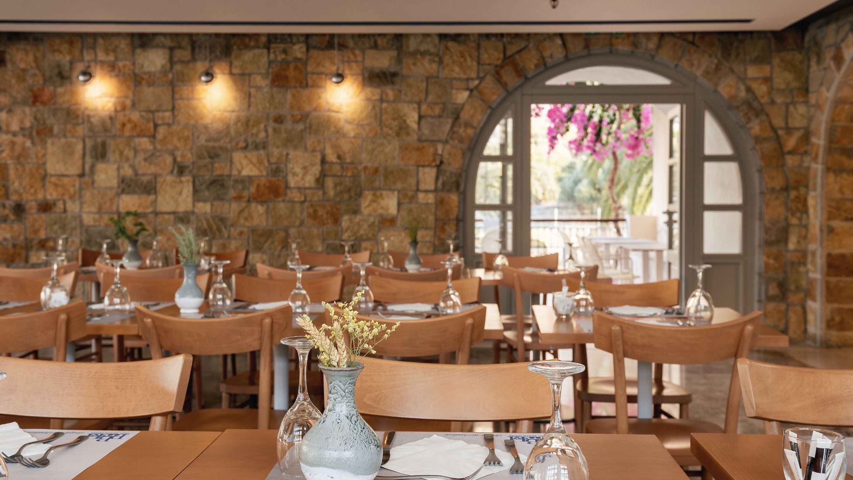 Un restaurante con paredes de piedra, mesas y sillas de madera.