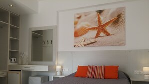 A bedroom with a bed, a desk, a mirror, and a wall-mounted artwork of a starfish.