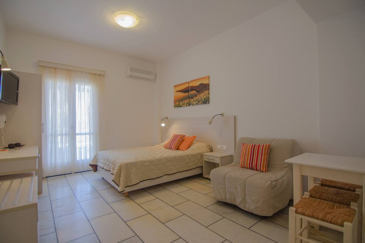 Un dormitorio con dos camas, un escritorio, una silla y un televisor.
