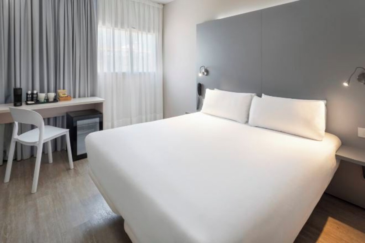 Une chambre d’hôtel moderne avec un grand lit, un bureau et une chaise.
