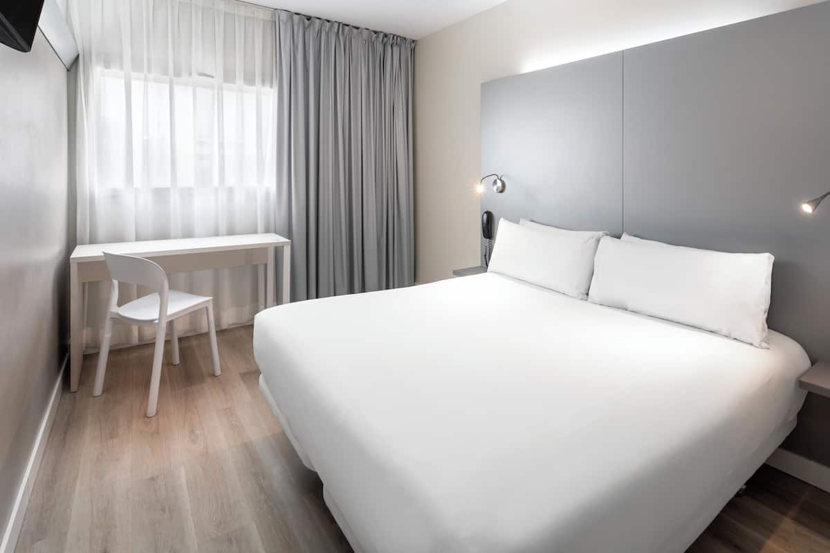 Une chambre d’hôtel moderne avec un grand lit, un bureau et une chaise.