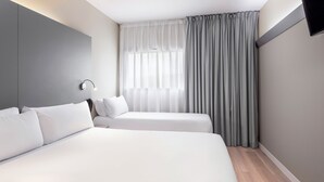 Une chambre d’hôtel avec un grand lit, deux tables de chevet, un bureau et une fenêtre avec des rideaux.