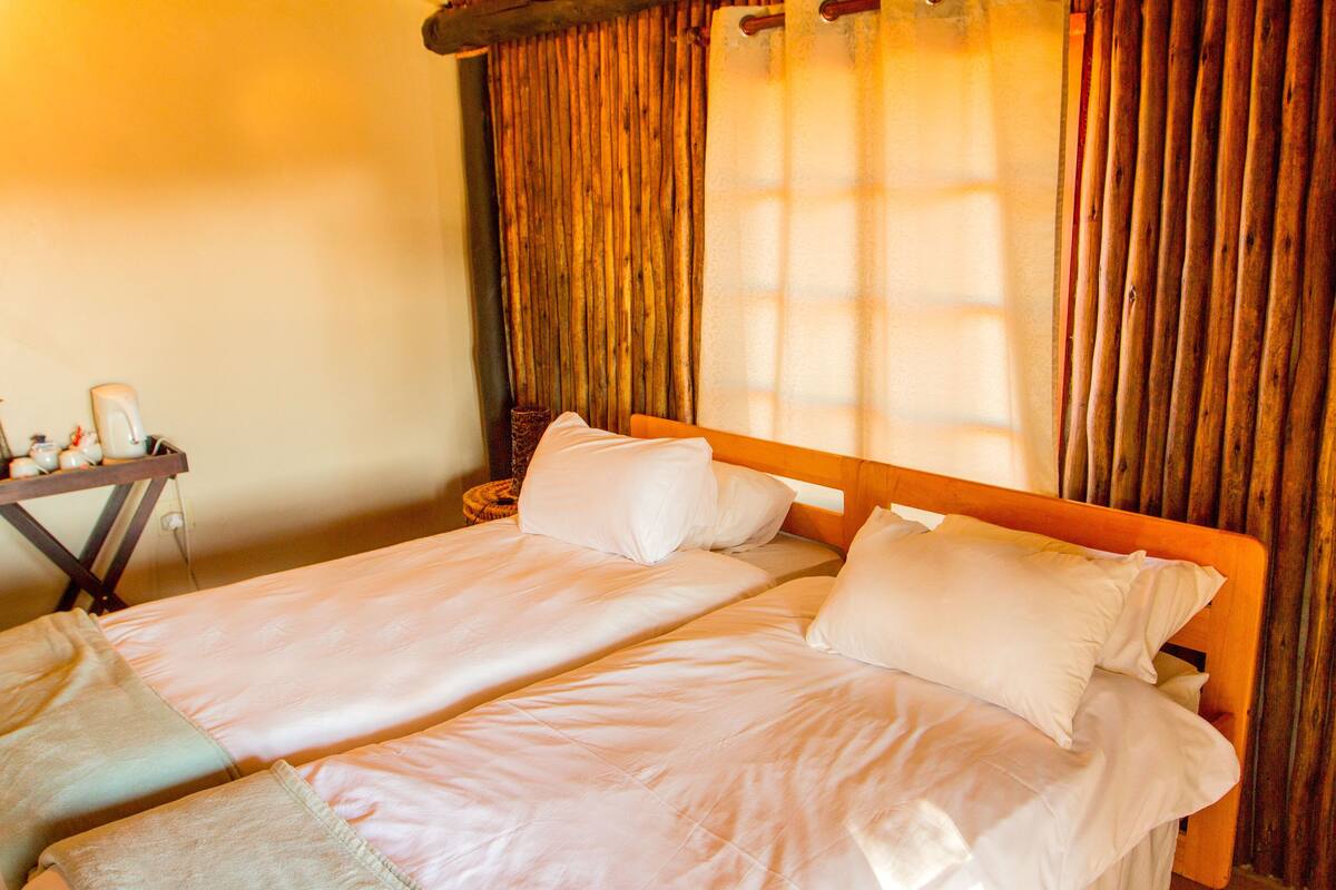 A double bed with white linens, a wooden headboard, and a nightstand with a lamp.