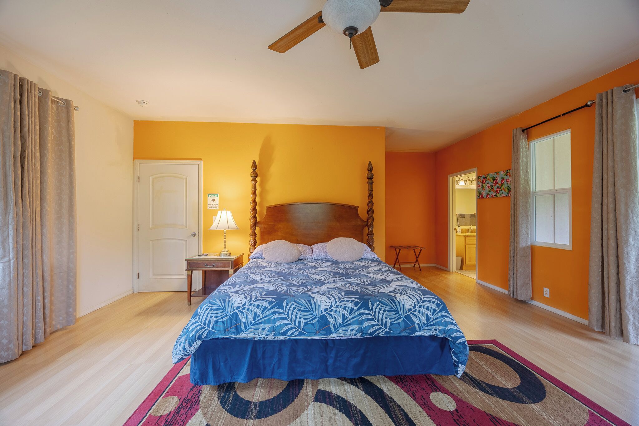 A bedroom with a bed, a nightstand, a ceiling fan, and a door.