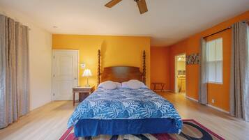 A bedroom with a bed, a nightstand, a ceiling fan, and a door.