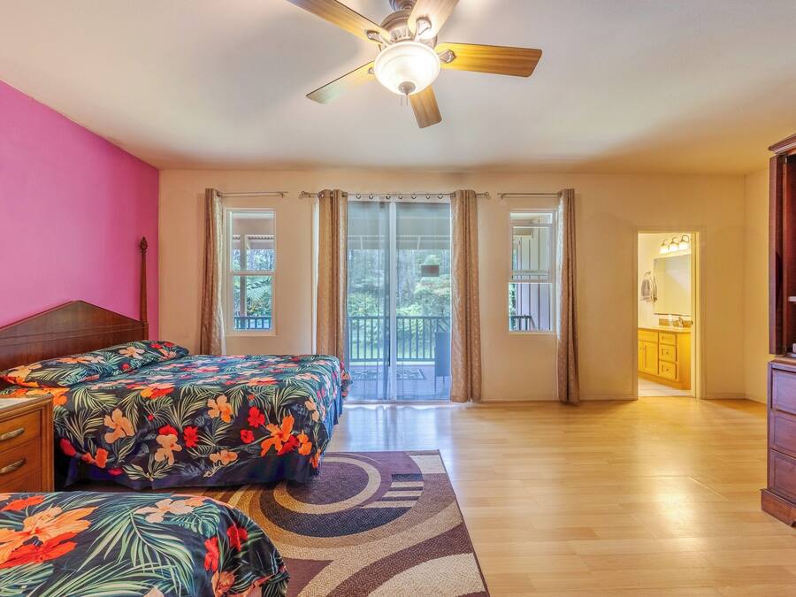 A bedroom with a bed, a nightstand, a dresser, a ceiling fan, and a view of the outside.