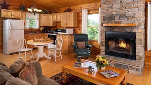 Un intérieur de chalet chaleureux avec une cheminée en pierre, des meubles en bois et un coin cuisine.
