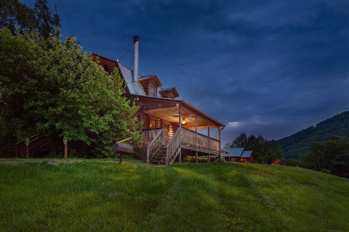 A wooden cabin with a covered porch, a chimney, and a staircase leading to the entrance.