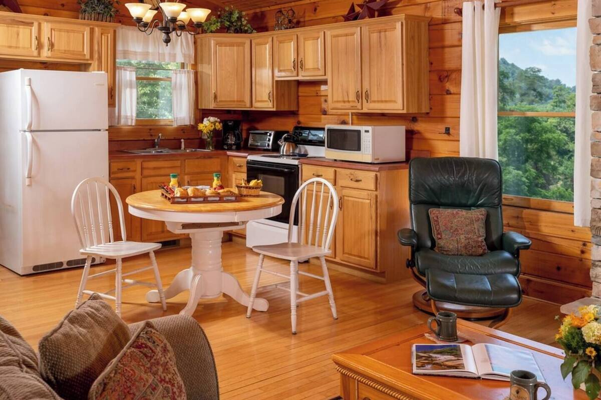 A cozy cabin-style kitchen with wooden cabinets, a refrigerator, a microwave, and a dining table with chairs.
