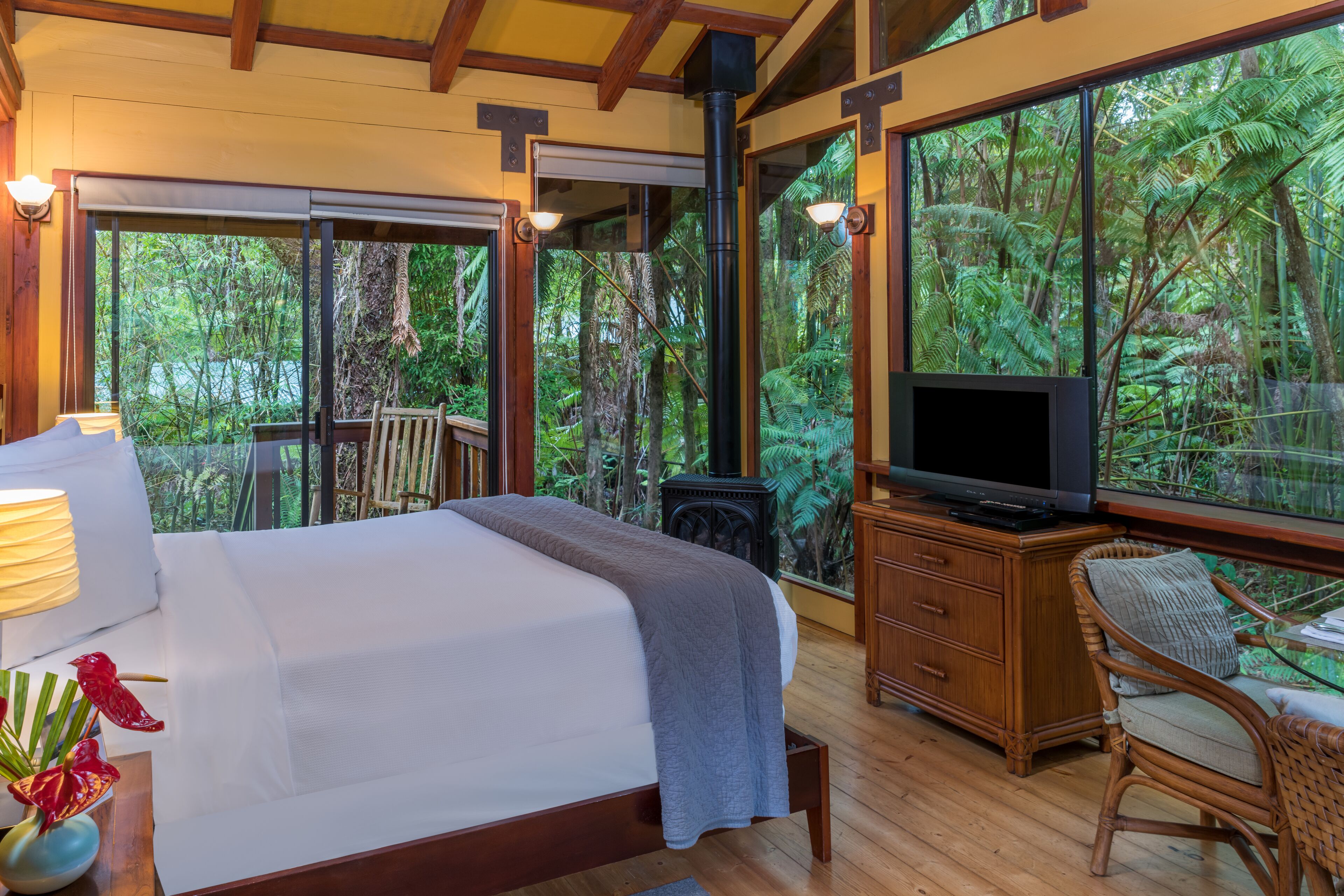 A bedroom with a bed, a television, a wooden dresser, and a chair.