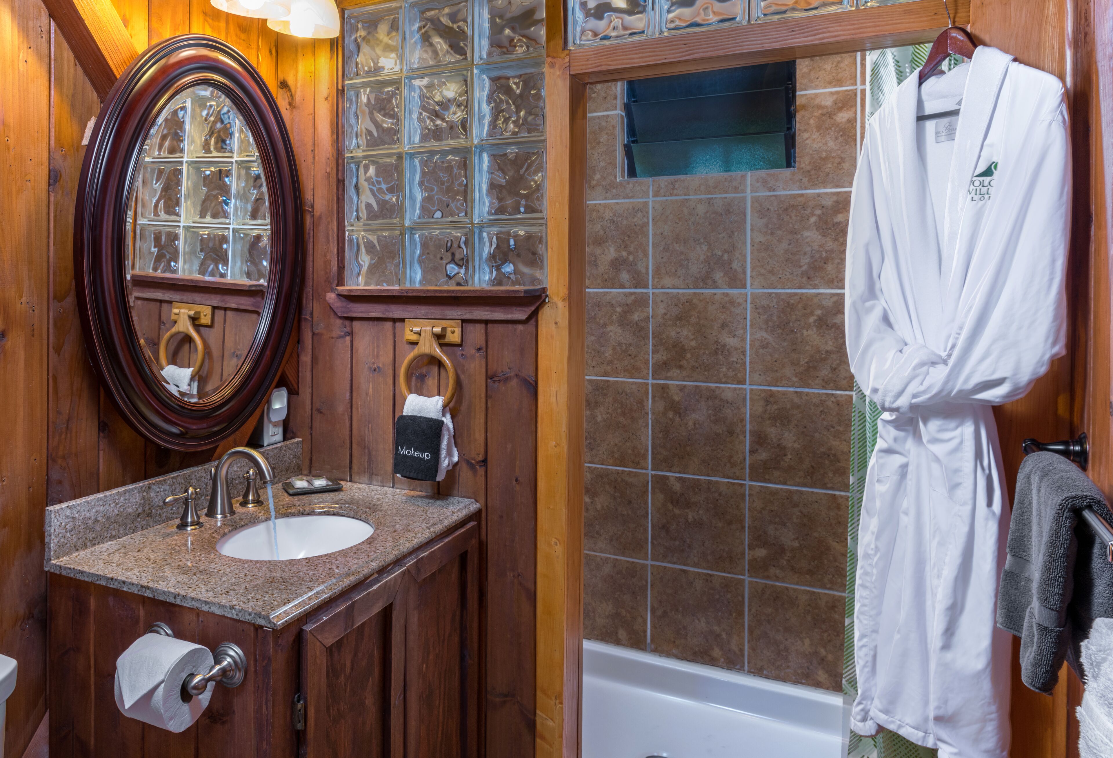 A bathroom with a wooden vanity, a sink, a mirror, and a bathtub.