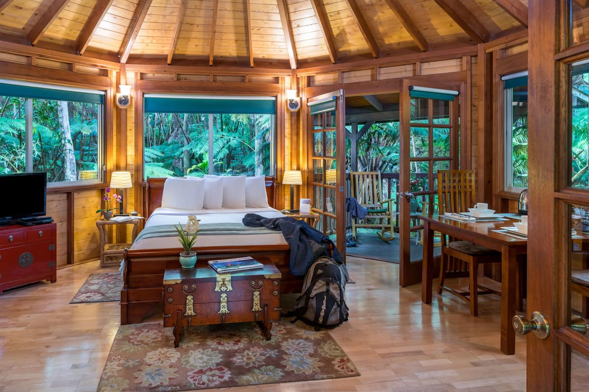 A wooden room with a bed, a desk, and a TV.